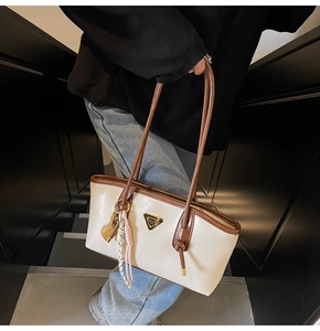 Détail du sac cabas blanc crème avec anses marron et plaque logo triangle doré