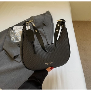 Close-up of black woven crescent bag with gold hardware on a white aesthetic background