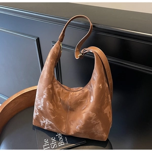 Detail of adjustable strap and marble pattern texture on brown leather tote bag