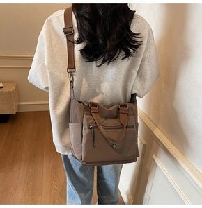Brown nylon tote bag shown as a crossbody with adjustable strap and metallic logo