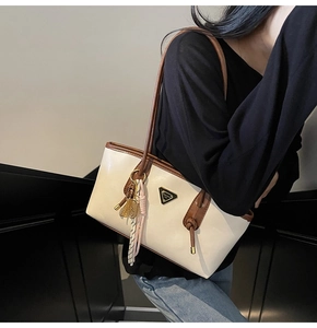 Détail du sac avec logo triangulaire en métal et pendentif raquette de tennis