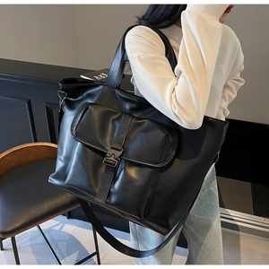 Détail d'un cabas noir en cuir PU brillant avec poche frontale pratique et boucle en métal