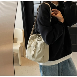 Dettaglio di una borsa a secchiello beige in nylon con coulisse portata a spalla moderna
