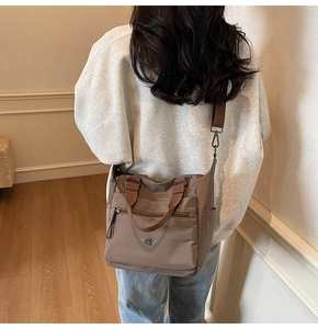 Detail of a brown multi-pocket nylon tote bag with adjustable straps in a cozy room