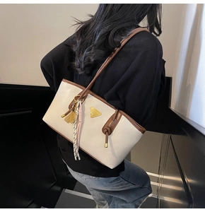 Sac cabas crème chic avec lanières marron et détail logo doré porté par modèle