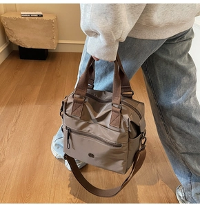Detail of khaki nylon tote bag with adjustable shoulder strap worn by a model