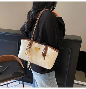 Détail du sac cabas blanc cassé avec bretelles marron et ornement de glands tressés