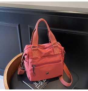 Detail of dark pink nylon tote bag with metal logo, top handles and shoulder strap