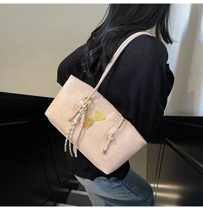 Vue détaillée du cuir synthétique rose et du logo triangulaire doré sur le sac fourre-tout