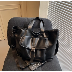 Gros plan sur un sac cabas noir avec boucle métallique sur un fauteuil en velours côtelé