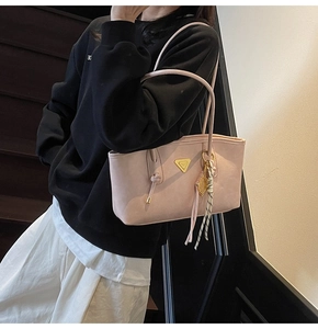 Détail du cabas en similicuir rose avec logo triangle métallique et pompon tressé