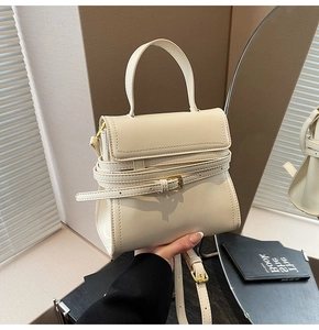 Détail du mini sac à bandoulière crème avec boucle à rabat et finitions dorées