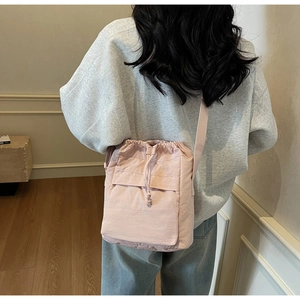 Vista posteriore di una modella con borsa a secchiello in nylon rosa chiaro e coulisse