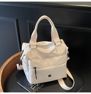 Detail of off-white waterproof nylon tote bag with wide strap on black chair