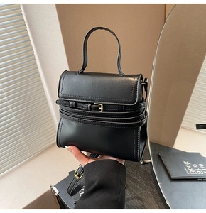 Détail du sac carré en cuir noir mat avec ceinture décorative et boucle dorée rétro