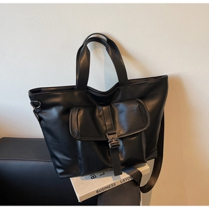 Vue détaillée du sac cabas noir avec poche à rabat et large bandoulière en tissu