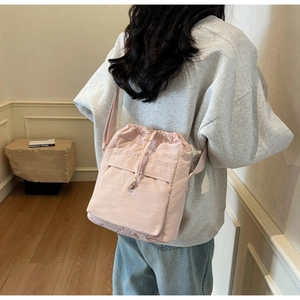 Vista lifestyle di una borsa a secchiello rosa con coulisse indossata da una modella