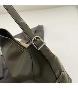 Close-up of dark green leather shoulder bag with polished silver buckle and adjustable strap