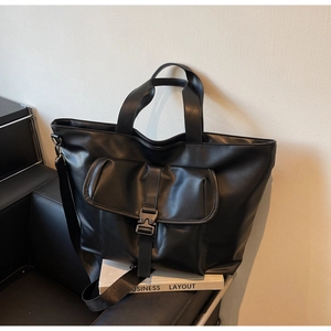 Détail macro du sac cabas en cuir mat noir avec boucle métallique et poche frontale