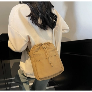 Vista posteriore di una modella con borsa a secchiello in nylon marrone chiaro