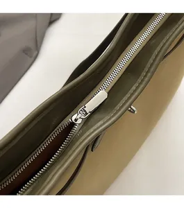 Macro shot of smooth silver metal zipper and fine stitching on olive green leather bag