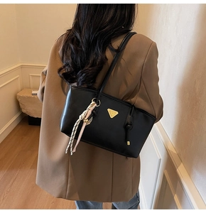 Vue détaillée du sac d'épaule en cuir noir avec logo doré et foulard sur un mannequin