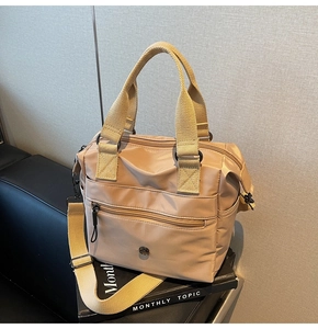 Macro detail of beige nylon tote bag with dual zipper pockets and adjustable shoulder strap