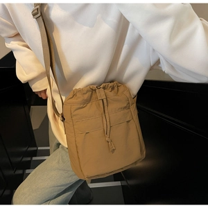 Dettaglio borsa a tracolla kaki con chiusura a coulisse e spallina in nylon regolabile