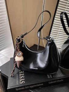 Sac Hobo noir brillant minimaliste avec breloque glace sur fond de livre