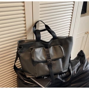Gros plan du sac cabas gris mat avec une grande poche frontale et une boucle noire