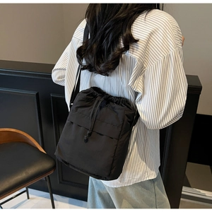 Dettaglio di una borsa a secchiello in nylon nero con coulisse e texture leggera