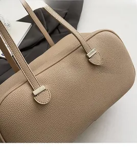 Close-up of litchi pattern leather texture and metal buckle on beige tote bag