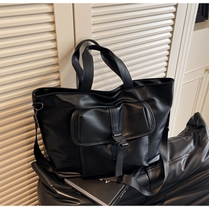 Détail du grand sac cabas noir avec poche avant à boucle et bandoulière réglable