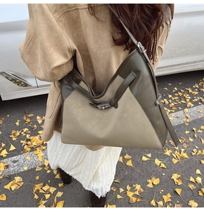 Detail of a large two-tone leather tote bag featuring a metallic turn-lock closure