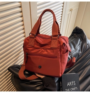 Detail of brick red nylon tote bag with zipper pocket and adjustable shoulder strap