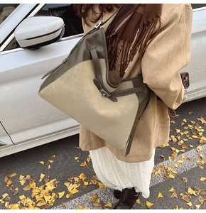 Detail of olive green and beige suede tote bag with V-shaped opening in autumn setting