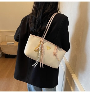 Détail du sac à bandoulière crème avec bordure rose et logo triangle sur modèle