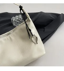 Detail shot of cream white handbag featuring soft leather texture and silver heart pendant