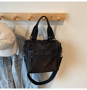 Detail of black nylon tote bag with multi-pocket design and adjustable shoulder strap