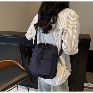 Vista posteriore della modella che indossa una borsa a secchiello in nylon blu scuro