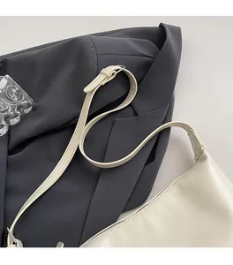 Detail of adjustable cream leather shoulder strap with silver metal buckle on tote bag