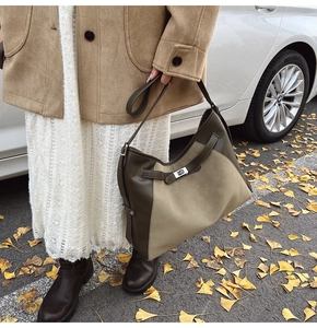 Detail of contrast color tote bag with metal twist lock and decorative belt strap