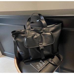 Détail du sac cabas noir avec poche à boucle sur fond minimaliste noir chic