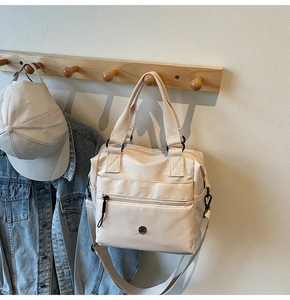 Detail of beige nylon tote bag with matte black hardware and adjustable shoulder strap