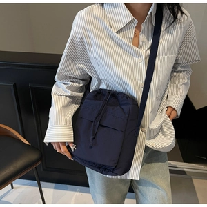 Dettagli della borsa a secchiello blu navy con coulisse, zip laterale e tracolla larga