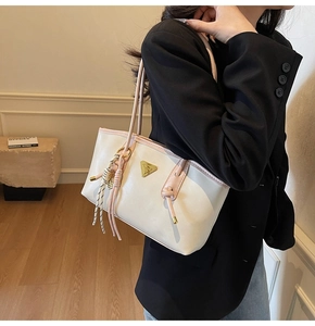 Détail du sac cabas blanc cassé avec anses roses et pendentif à pompon élégant