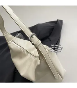 Detail of adjustable shoulder strap with silver metal buckle on a cream crescent bag