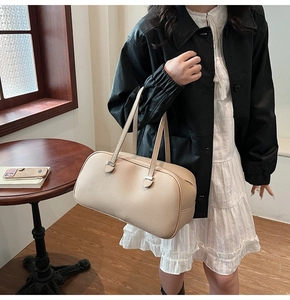 Close-up of beige lychee texture leather on a stylish minimalist Boston pillow bag