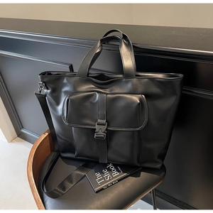 Détail d'un grand sac cabas noir avec poche à boucle et bandoulière en tissu réglable