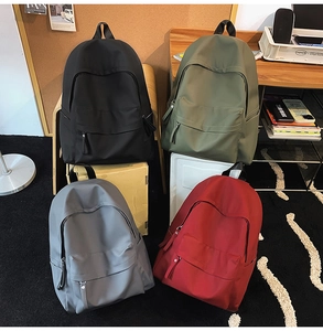 Detail view of four-color casual backpacks in black, green, gray and red nylon